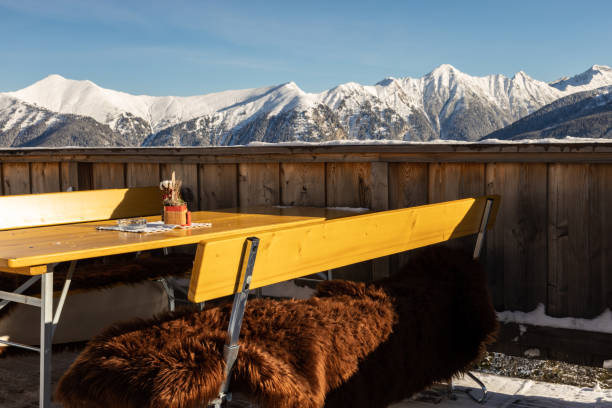 mesa e bancos com peles em um café de montanha com vista para as montanhas alpinas cobertas de neve, áustria, salzburgo - apres ski ski restaurant mountain - fotografias e filmes do acervo