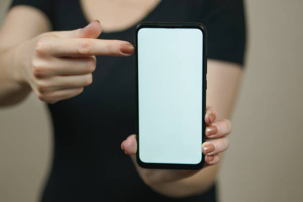 istock The female finger points to the phone white screen. 1450755699