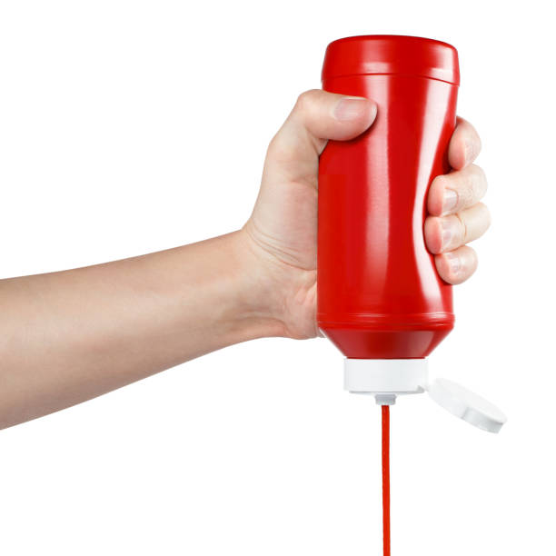 istock Hand squeezing ketchup out of a plastic bottle on white 1450757573
