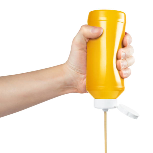istock Hand squeezing mustard out of a plastic bottle on white 1450757644