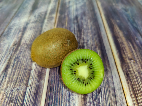 Whole kiwi fruit and half. Tropical green fruit on a wooden table. Close-up