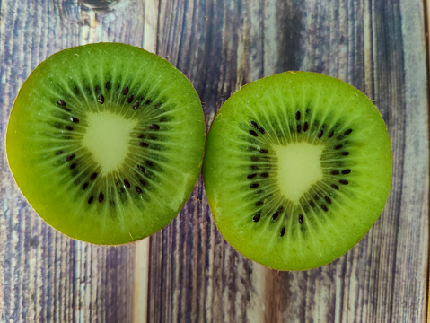 Two half tropical fruit kiwi on a wooden table. View from above. Macro photography