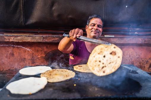 Indian street vendor preparing food - chapatti, flat bread, in The Pink City of Jaipur, Rajasthan, India.  Jaipur is known as the Pink City, because of the color of the stone exclusively used for the construction of all the structures.