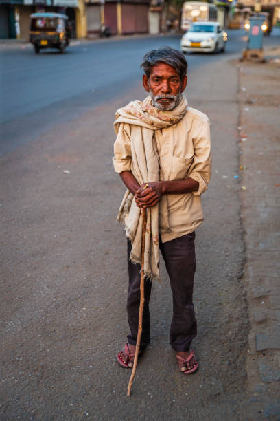 Poor Indian man standing on a street and asking for support.