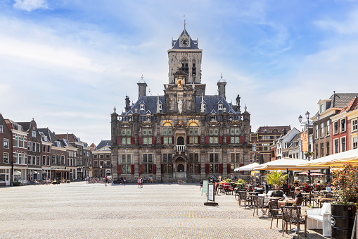 Delft, Netherlands, June 7, 2021; People enjoy the terrace on the market square with the city hall in Delft in the background.