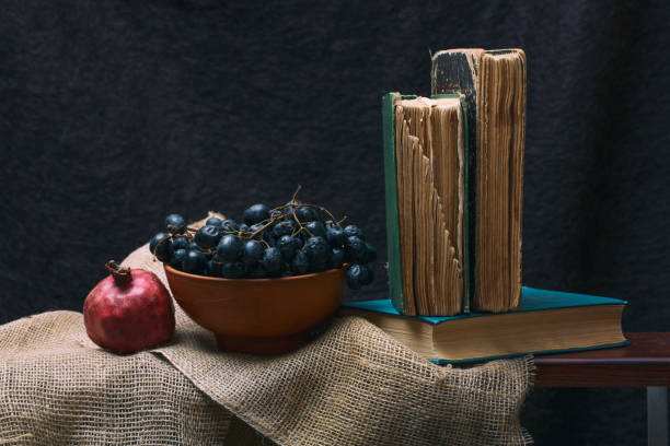 istock Ripe red pomegranates, grapes and books on the table 1450770169