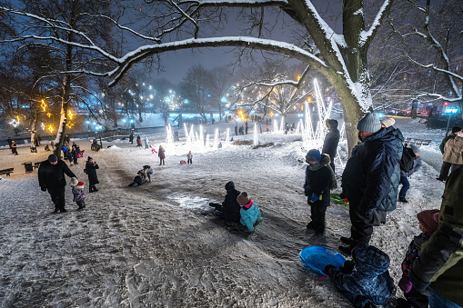 Latvia, Riga - December 17, 2022: Families with children enjoying themselves at an ice slide in Bastejkalns park