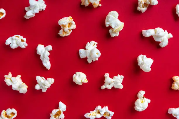 Photo of Popcorn pattern on red background. Top view, flat lay