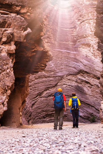 Two young backpackers watching sunbeams in the hollow of the Quebrada das Conchas amphitheater in Cafayate, Argentina