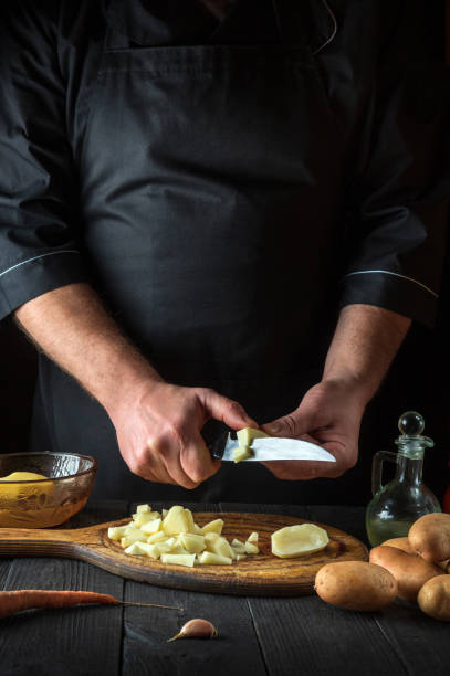istock The chef cuts raw potatoes into pieces with a knife before preparing breakfast or dinner. Close-up of a cook hands while working in a restaurant kitchen. 1450781400