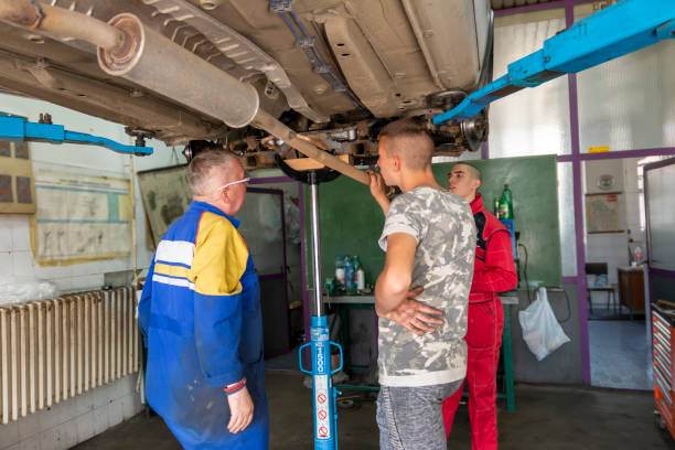 istock Male tutor with students on auto mechanic apprenticeship course at college 1450785715
