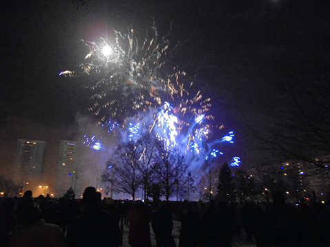 Finish of firework explosion during New year pyrotechnics show with blue sparks and thick dust.