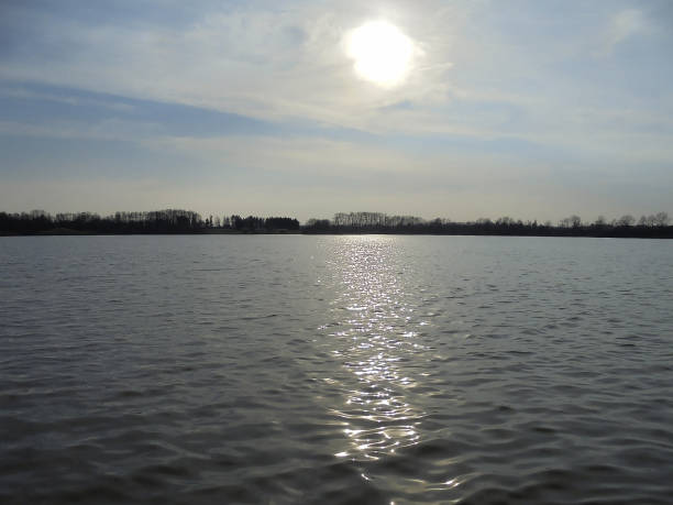 istock Vast wavy water surface and half-covered sun over horizon. 1450788979