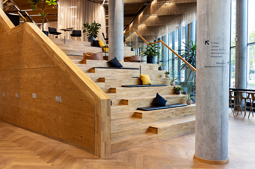 Creative workspace with workstations on wooden steps. Innovative office with cushions and pillows on wooden staircase.