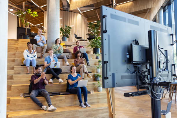 Business team sitting on steps and applauding after a video conference