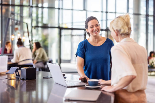 istock Two businesswomen standing at cafe counter discussing work 1450789127