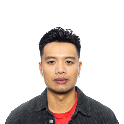 Close-up portrait of young asian man staring at camera. Confident male on white background.