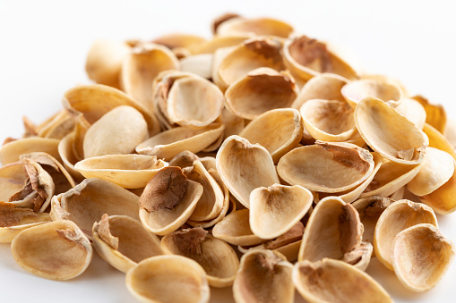 Heap of salted pistachio shells on white background - close up view