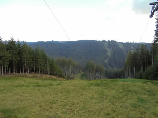 Beskydy mountain horizon under cold sun. Forests,meadow and hills in cloudy weather.