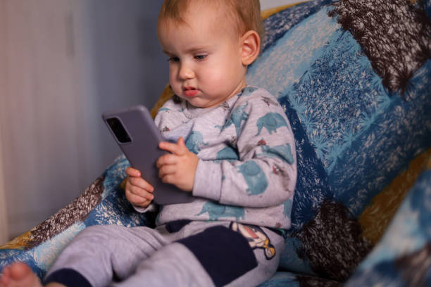 istock Cute young little boy typing on smart phone 1450798305