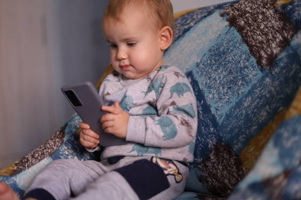 istock Cute young little boy typing on smart phone 1450798481
