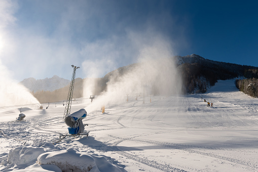 Snowmaking machine snow cannon or gun in action on a cold sunny winter day in ski resort Kranjska Gora, Slovenia