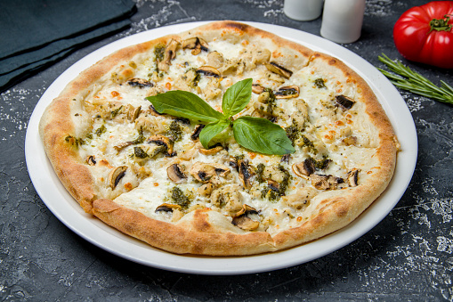 Pizza with chicken, cheese and mushrooms on dark table