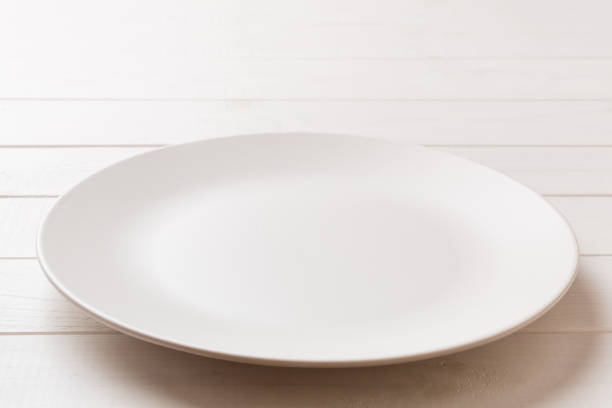 istock Perspective view of empty light plate on wooden background. Empty space for your design 1450809627