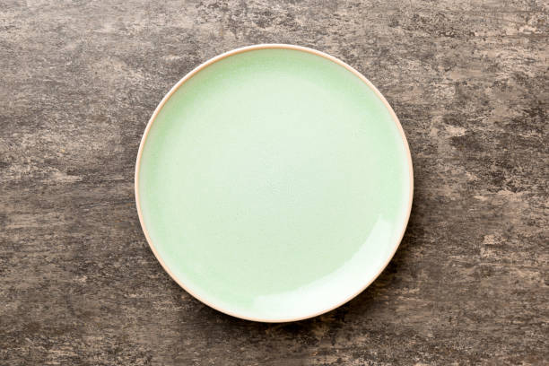 istock Top view of empty green plate on cement background. Empty space for your design 1450809652