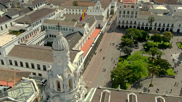Aerial footage of famous buildings in the colonial city of Quito with the country's flag on the roof