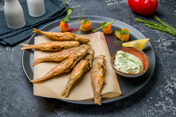 istock fried surmullet on black plate with sauce on dark table 1450810748
