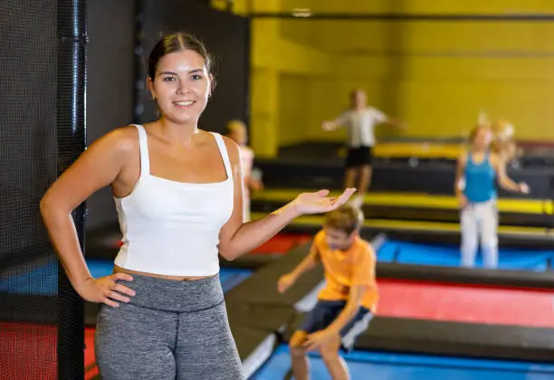 Photo of Woman trampolining coach against the background of children playing and jumping on a trampoline