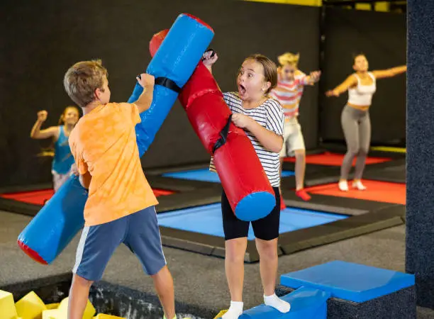 Photo of Tween girl having fun on battle beam with boy