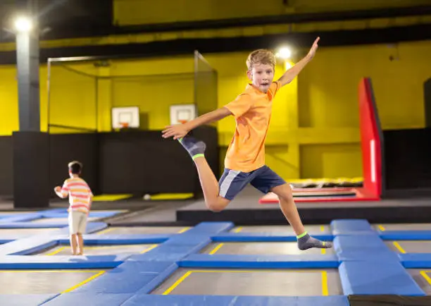 Photo of Preteen boy bouncing on trampoline in indoor amusement park