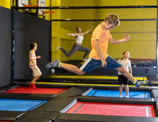 Photo of Preteen boy bouncing on trampoline in indoor amusement park