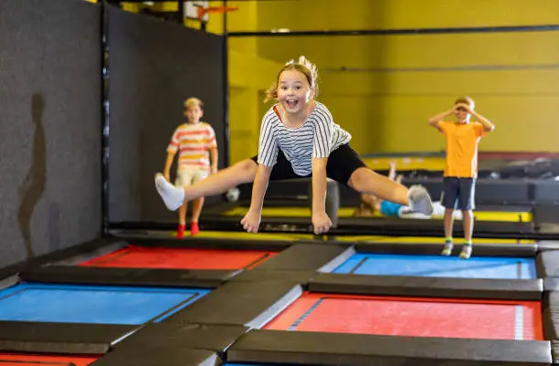 Photo of Tween girl doing split in jump in indoor trampoline arena