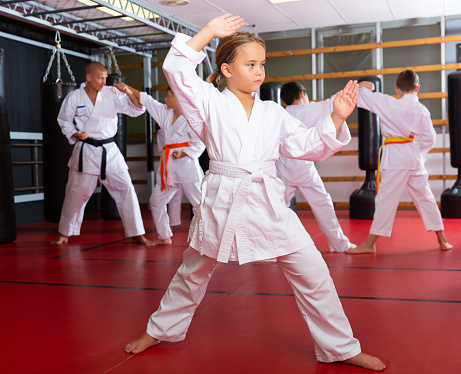 Portrait of schoolchild girl practicing new moves with master during karate class