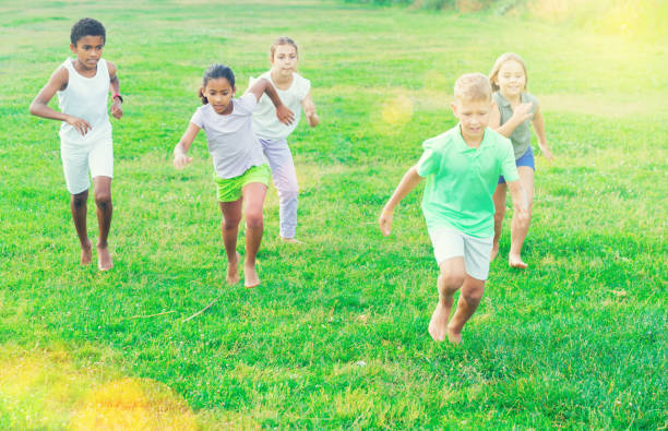 Group of children having fun together outdoors running Group of laughing children having fun together outdoors running child 10 11 years 8 9 years cheerful stock pictures, royalty-free photos & images