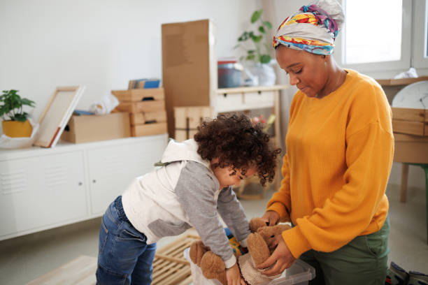Mother and son packing toy and belongings in small cozy apartment