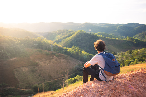 Man sitting on top of the mountain enjoying the landscape and nature. Concept of tranquility and mental well-being through travel or contact with nature.