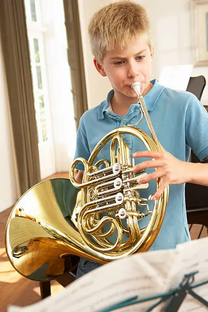 Boy playing French horn at home