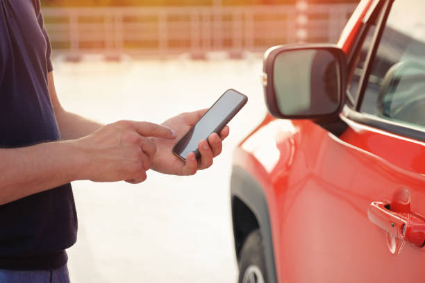 istock A man uses a mobile phone while standing near his car outdoors. Modern lifestyle 1450851293