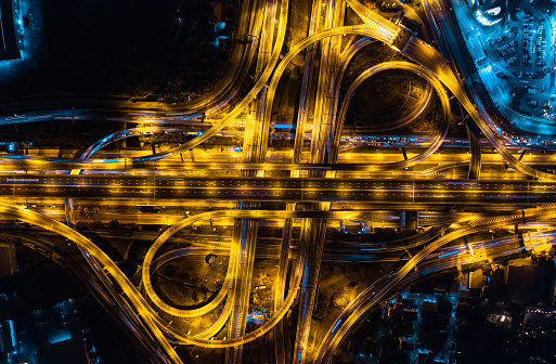 Aerial top view of Modern Multilevel Motorway Junction with Toll Highway, Road traffic an important infrastructure, Expressway Road and Roundabout, Night scene, Transportation and travel concept.