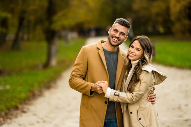 istock Happy couple looking at camera in autumn park. 1450862286