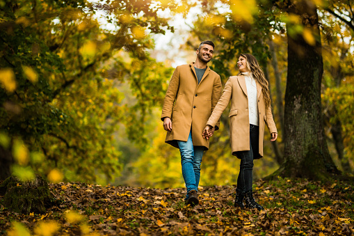 Beautiful young couple walking and having fun in autumn park.