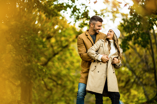 Beautiful young couple embracing and looking at each other in the park on autumn day.