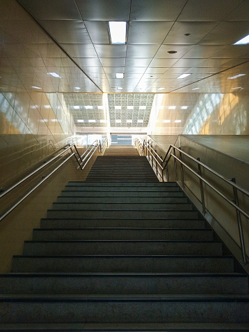 Perspective view of dark and long stairway at entrance to MRT Station at Bendungan Hilir in Jakarta. No people.