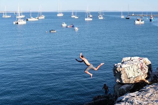 Cascais, Portugal – October 01, 2022: A young man diving in the seawater in the Cascais area in Lisbon state in Portugal