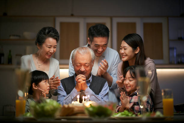 three generation asian family celebrating grandpa's birthday at home stock photo