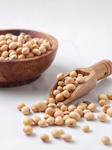 Soybean or soya bean in a wooden bowl on white background. Selective focus